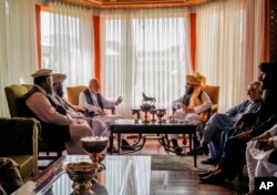 In this handout photograph released by the Taliban, former Afghan President Hamid Karzai, center left, senior Haqqani group leader Anas Haqqani, center right, Abdullah Abdullah, second right, head of Afghanistan's National Reconciliation Council.