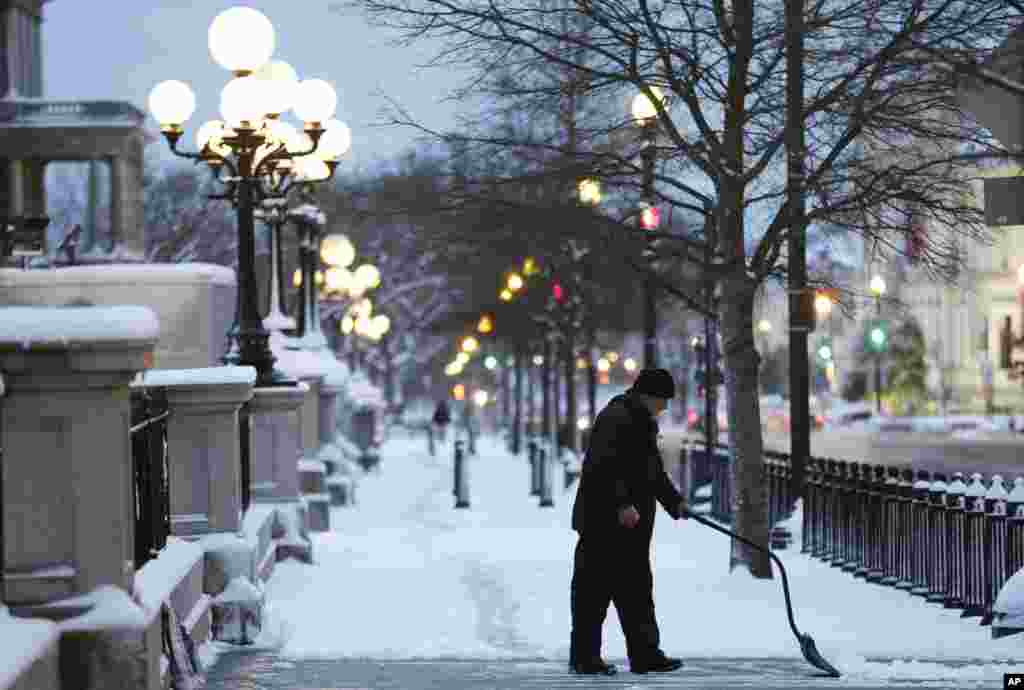 A man clears the sidewalk near the Eisenhower Executive Office Building in the White House complex in Washington, March 17, 2014.