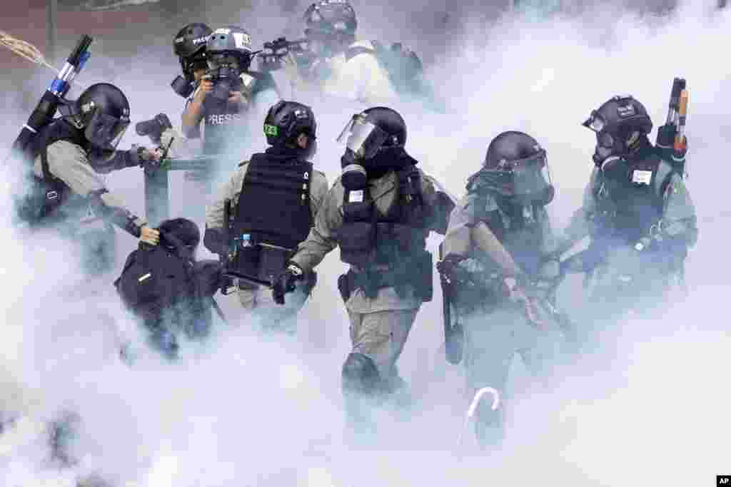 Police in riot gear move through a cloud of smoke as they detain a protester at the Hong Kong Polytechnic University in Hong Kong, Monday, Nov. 18, 2019.