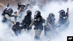 Police in riot gear move through a cloud of smoke as they detain a protester at the Hong Kong Polytechnic University in Hong Kong, Monday, Nov. 18, 2019.