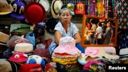 ស្រ្តី​ម្នាក់​លក់​វត្ថុ​អនុស្សាវរីយ៍​ឲ្យ​ភ្ញៀវ​ទេសចរ​ដែល​ទៅ​ទស្សនា​ផ្សារ​អណ្តែត​លើ​ទឹក Amphawa នៅ​ខេត្ត Samut Songkhram ប្រទេស​ថៃ។ 