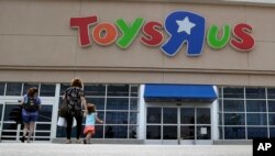 FILE - Shoppers walk into a Toys R Us store, in San Antonio, Texas, Sept. 19, 2017. Toys R Us says it will be closing some U.S. stores and converting others to cobranded locations as it continues to deal with its financial restructuring following its bankruptcy filing.