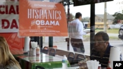 Spanish language election campaign signs promoting President Barack Obama hang on the windows at Lechonera El Barrio Restaurant in Orlando, Florida, October 26, 2012. 