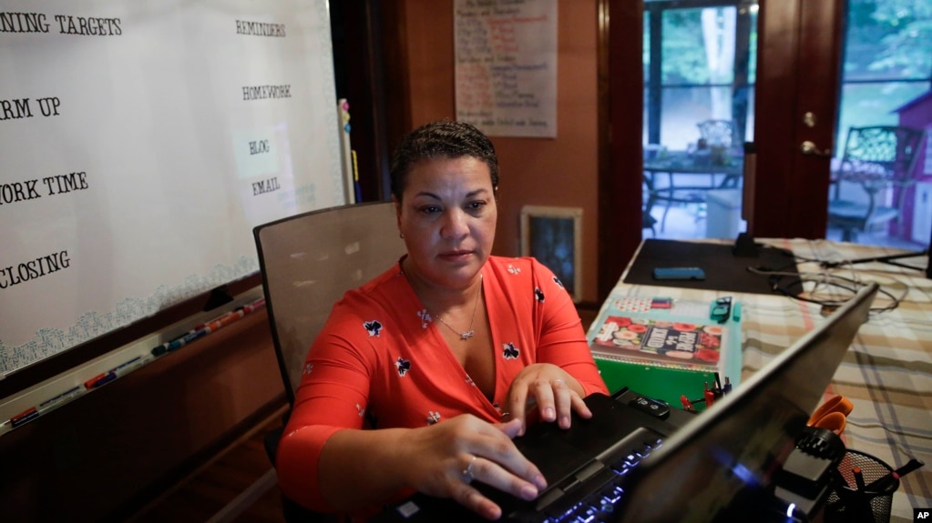 Aimee Rodriguez Webb works on her computer reading emails at her dining room table that she set up as a virtual classroom for a Cobb County school, on Tuesday, July 28, 2020, in Marietta, Ga. (AP Photo/Brynn Anderson)