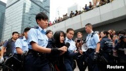 Seorang pengunjuk rasa diseret keluar dari lokasi protes oleh pihak berwenang Hong Kong (11/12). Lokasi di luar gedung pemerintah Hong Kong ini biasanya digunakan sebagai kamp utama para pemrotes pro-Demokrasi.