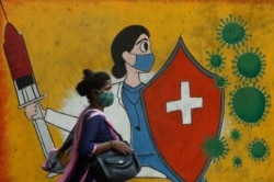 Seorang perempuan berjalan melewati grafiti di tengah pandemi COVID-19 di Mumbai, India, 10 Mei 2021. (REUTERS/Francis Mascarenhas)