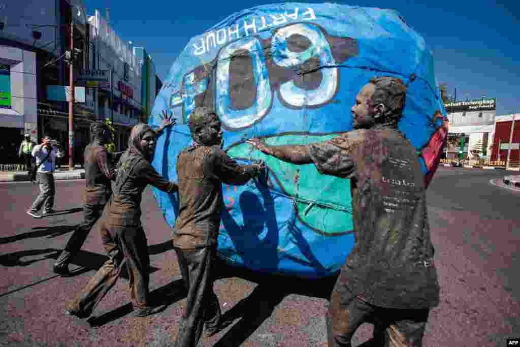 Aceh students coat their bodies in mud and roll a globe (symbolizing the Earth) during an Earth Day celebration in Banda Aceh, Indonesia.