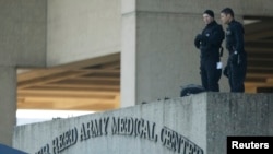 FILE - Security personnel man an observation post on the roof to the entrance of the Walter Reed Army Medical Center in Bethesda, Maryland.