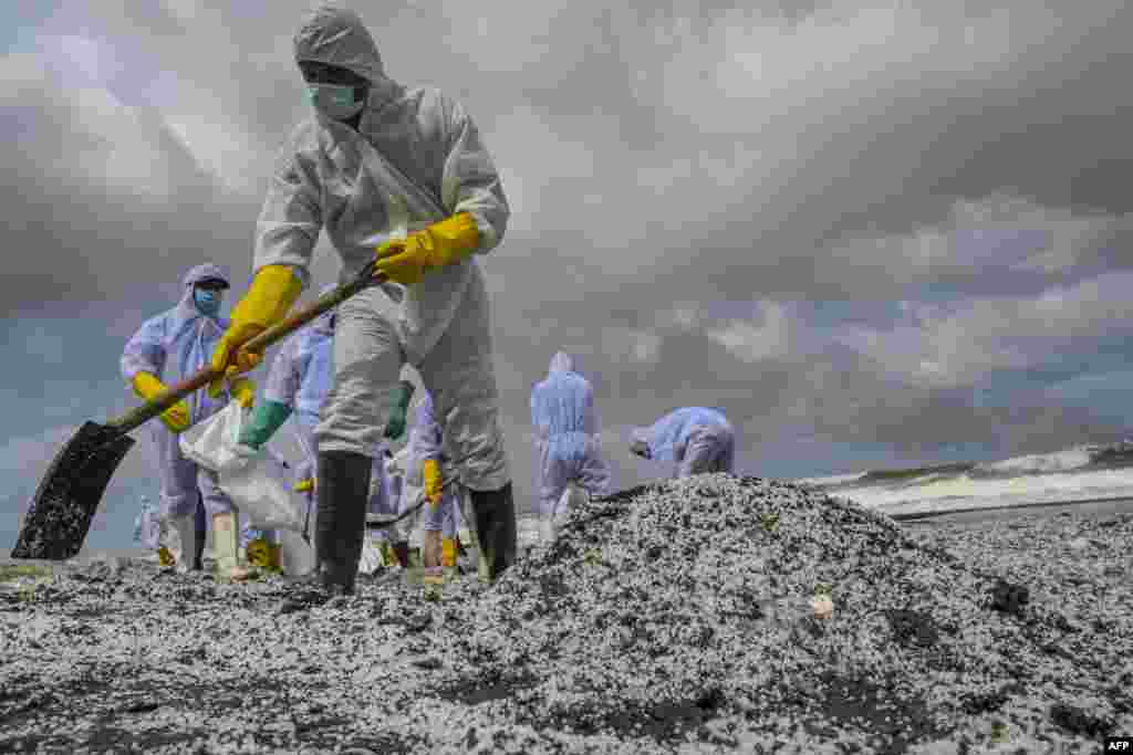 Sri Lankan Navy soldiers remove debris washed ashore from the Singapore-registered container ship MV X-Press Pearl, which has been burning for the ninth consecutive day in the sea off Sri Lanka's Colombo Harbour, on a beach in Colombo.