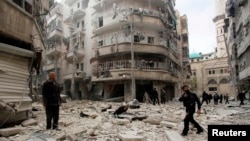 Men inspect the damage at a site hit by what activists said were two barrel bombs dropped by forces loyal to Syria's President Bashar al-Assad in Aleppo's al-Shaar neighborhood Feb. 26, 2015.