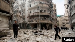 FILE - Men inspect the damage at a site hit by what activists said were two barrel bombs dropped by forces loyal to Syria's President Bashar al-Assad in Aleppo's al-Shaar neighborhood, February 26, 2015. 