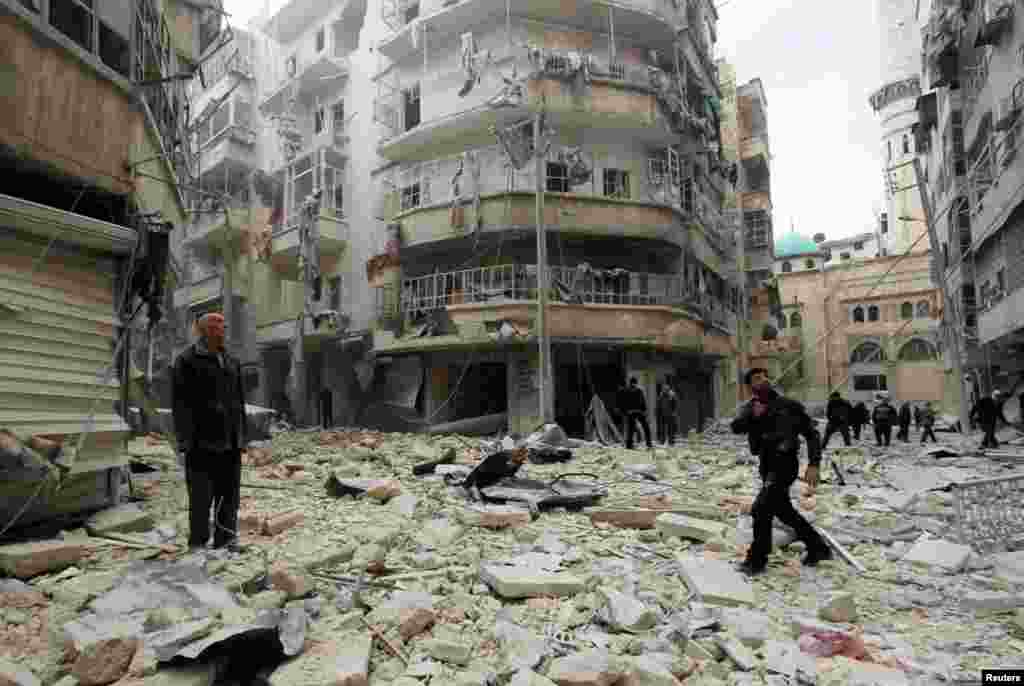 Men inspect the damage at a site hit by what activists said were two barrel bombs dropped by forces loyal to Syria&#39;s President Bashar al-Assad in Aleppo&#39;s al-Shaar neighborhood.