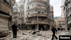 Para pria menginspeksi kerusakan di lokasi ledakan dua bom oleh pasukan yang loyal pada Presiden Bashar al-Assad di Aleppo (26/2). (Reuters/Rami Zayat)