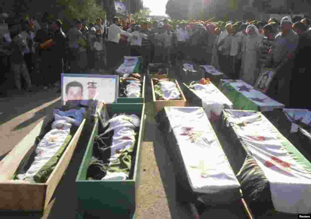 Syrian residents gather in front of the bodies of people, whom protesters say were killed by forces loyal to Syria's President Bashar al-Assad, during their funeral in Dara'a June 9, 2012. 