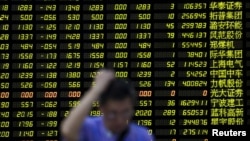 An investor stands in front of an electronic board showing stock information in Shanghai, China, August 24, 2015. (Reuters)
