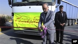 Head of the Atomic Energy Organization of Iran, Ali Akbar Salehi, cuts a ribbon during a ceremony, as a truck containing Iran's first domestically mined raw uranium arrives at the Isfahan uranium conversion facility, 05 Dec 2010