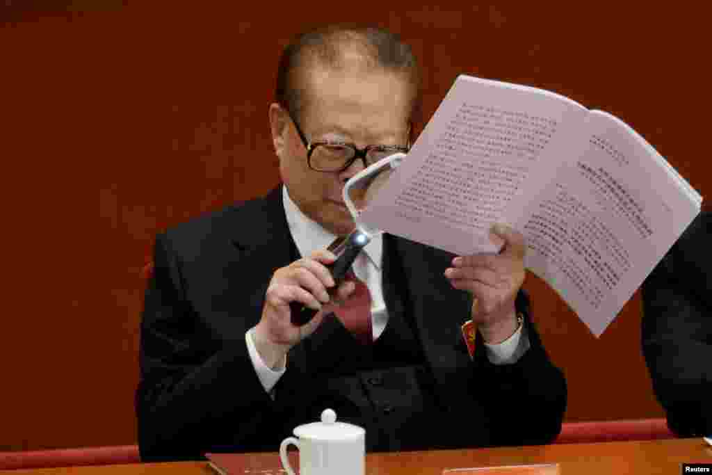 Former Chinese President Jiang Zemin uses a magnifier as he reads Chinese President Xi Jinping&#39;s report during the opening of the 19th National Congress of the Communist Party of China at the Great Hall of the People in Beijing.