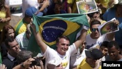Anggota Kongres Jair Bolsonaro memegang bendera Brazil dalam unjuk rasa menentang Presiden Dilma Rousseff, yang berkuasa pada saat itu di Brasilia, Brazil, 13 Maret 2016.