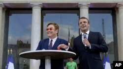 Presiden Perancis Emmanuel Macron (kanan) dan Sir Elton John di halaman Istana Elysee, Paris, Perancis, 21 Juni 2019. (Foto: dok). 
