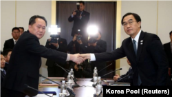 El jefe de la delegación norcoreana, Ri Son Gwon, se da la mano con su par surcoreano, Cho Myoung-gyon, mientras intercambian documentos tras su encuentro en la villa fronteriza de Panmunjeom, en la zona desmilitarizada que divide a ambos países, 9 de ene