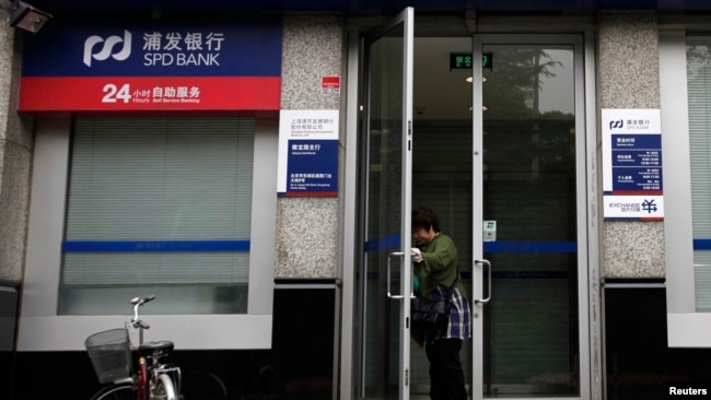 一名女士打开上海浦东发展银行开设在北京的一所支行的大门。（2011年7月6日）