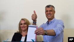 Perdana Menteri Kosovo Hashim Thaci, bersama istrinya Lumnije, memberikan suara di sebuah TPS di ibukota Pristina, Minggu (8/6). (AP/Visar Kryeziu)