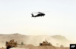 FILE - A US military helicopter flies over the site of a suicide bomb that struck a NATO convoy in Kandahar south of Kabul, Afghanistan, Aug. 2, 2017.