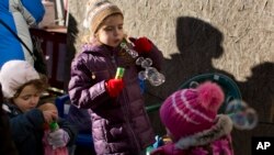 FILE - Children of internally displaced Ukrainian people, who abandoned their homes in Donetsk, play with donated toys during a food distribution drive in central Kyiv, Oct. 25, 2014.