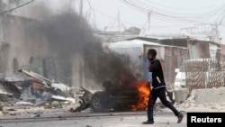 A man talks on his mobile phone as he walks at the scene of an explosion near the entrance of the airport in Somalia's capital Mogadishu, Feb. 13, 2014. 
