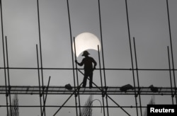 FILE - A partial solar eclipse is seen as a labourer works at a construction site in Phnom Penh, Cambodia.