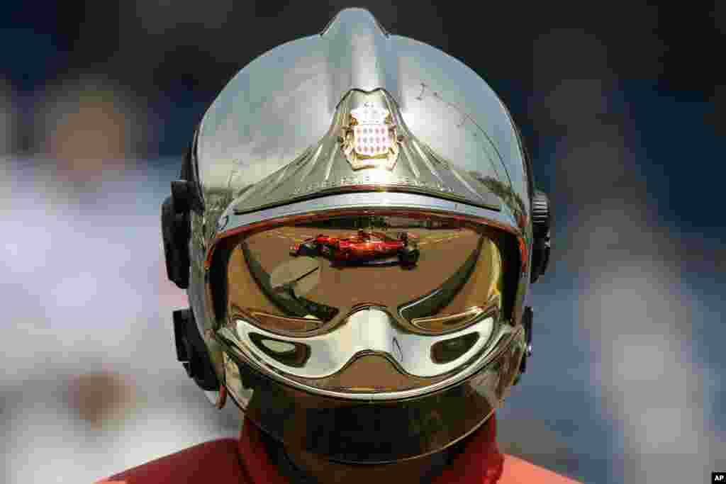 Ferrari driver Kimi Raikkonen of Finland is reflected on a firefighter's helmet as Raikkonen steers his car during the second free practice at the Formula One Grand Prix at the Monaco racetrack in Monaco.