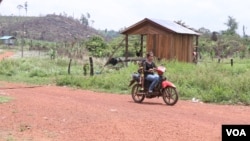 A woman rides a motorcycle on a road in Pursat province, Cambodia, April 9, 2019 (Sun Narin/VOA Khmer)