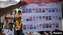 People watch as electoral officials show ballot papers during vote counting at a polling station in Jakarta, April 9, 2014.