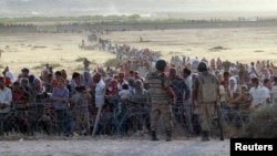 In this Sept. 2014 file photo, Turkish soldiers stand guard as Syrians wait behind border fences near the southeastern town of Suruc, Sanliurfa province. (REUTERS)