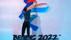 FILE - A crew member leaps to fix a logo for the 2022 Beijing Winter Olympics before a launch ceremony to reveal the motto for the Winter Olympics and Paralympics in Beijing, Sept. 17, 2021.