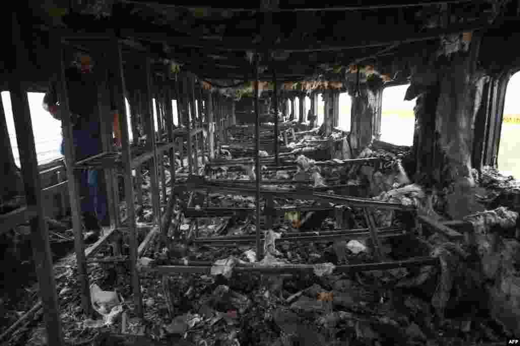 A man walks inside a burned train car a day after a passenger train caught on fire, killing at least 74, in Rahim Yar Khan, Pakistan.