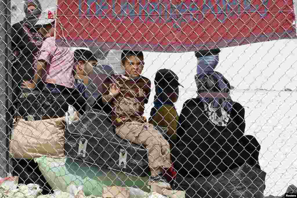 A group of Syrian refugees wait for a bus at the Al-Zaatri refugee camp in the Jordanian city of Mafraq, near the Syrian border, June 25, 2013. 