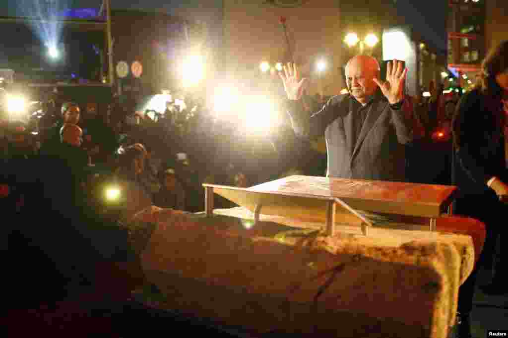 Former Soviet President Mikhail Gorbachev makes an impression with his hands in cement as he visits the former Berlin Wall border crossing point Checkpoint Charlie, in Berlin, Nov. 7, 2014. 