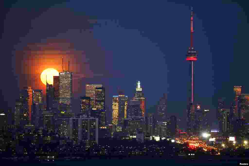 The moon rises behind the Canadian landmark CN Tower, and the skyline of Toronto, Nov. 25, 2015.