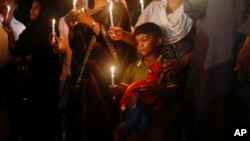 A Bangladeshi boy holds a Spiderman toy in one hand and a lighted candle in the other as he joins elders in paying tribute to those killed in the attack at the Holey Artisan Bakery in Dhaka.