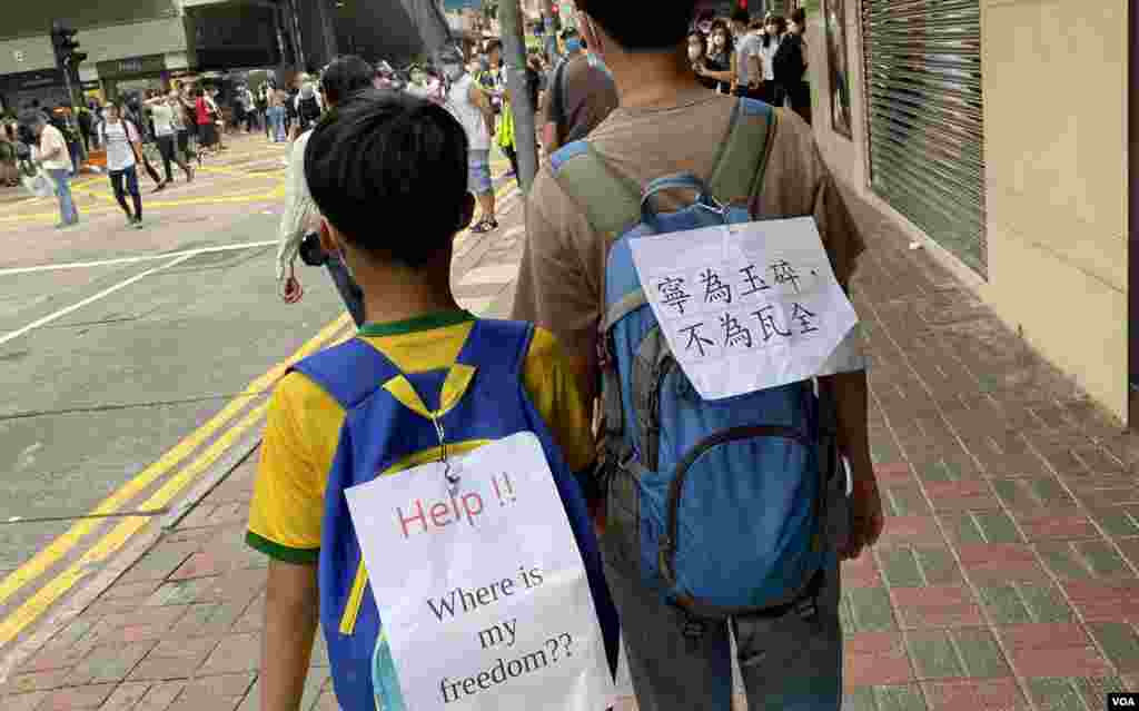 40多歲的香港市民王女士帶同10歲的兒子上街，他們在背包上貼上標語。(美國之音湯惠芸拍攝)