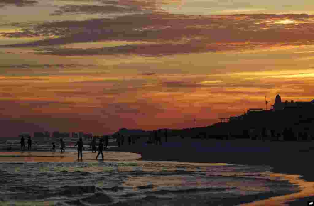 Para pengunjung menikmati suasana matahari terbenam di pantai Seaside, Florida.