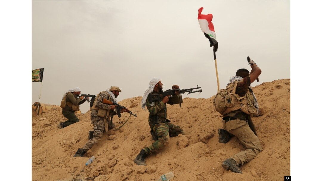 FILE - Fighters from Badr Brigades Shiite militia clash with Islamic State group militants at the front line on the outskirts of Fallujah, Anbar province, Iraq, June 1, 2015.