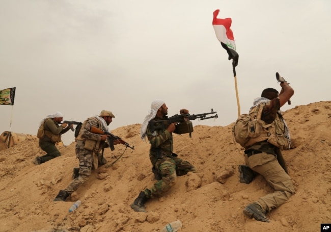 FILE - Fighters from Badr Brigades Shiite militia clash with Islamic State group militants at the front line on the outskirts of Fallujah, Anbar province, Iraq, June 1, 2015.