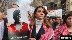 约旦王后拉尼娅在安曼举行的一次游行中手持被伊斯兰国恐怖组织处决的约旦飞行员穆斯·卡萨斯贝的照片，悼念这位遭火刑处死的飞行员。（2015年2月6日）