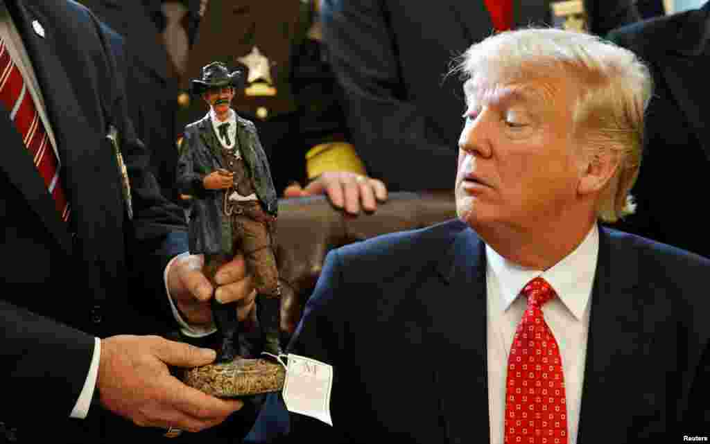 U.S. President Donald Trump receives a figurine of a sheriff during a meeting with county sheriffs at the White House in Washington, D.C.