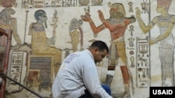 A worker cleans a chapel wall at Khonsu Temple at Karnak in Luxor. (Mohamed Abdelwahab for USAID)