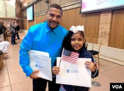 Dominican-American Luz Estrella Luna, 8, shows off her certificate of U.S. citizenship alongside her dad, Luis, after a citizenship ceremony in New York, May 5, 2017. (R. Taylor/VOA)