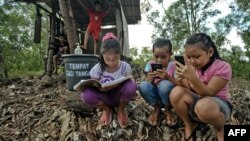Para pelajar di Desa Bukit Temulawak, Yogyakarta mengikuti kelas daring selama pandemi, menggunakan telepon genggam dengan akses internet yang masih terbatas (AFP). 