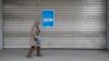 Una mujer pasa por una tienda por departamentos de la cadena minorista alemana Galeria del grupo Galeria Karstadt Kaufhof el 2 de abril de 2020 en Berlín, cerrada como la mayoría de las tiendas en una medida para limitar la propagación del nuevo coronavirus. 
